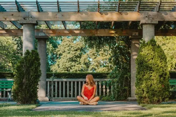 woman in red sitting on a concrete patio with pergola